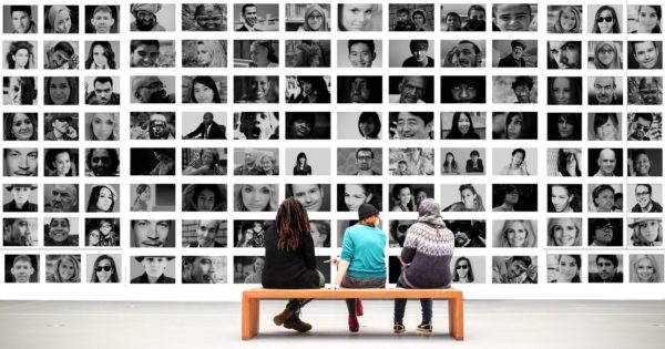 Des personnes devant une multitude de photos de visages